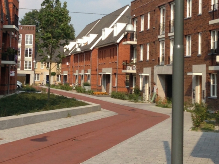 Opgeleverde bakstenen woningen langs een rood voetpad in een MGM-wijk.